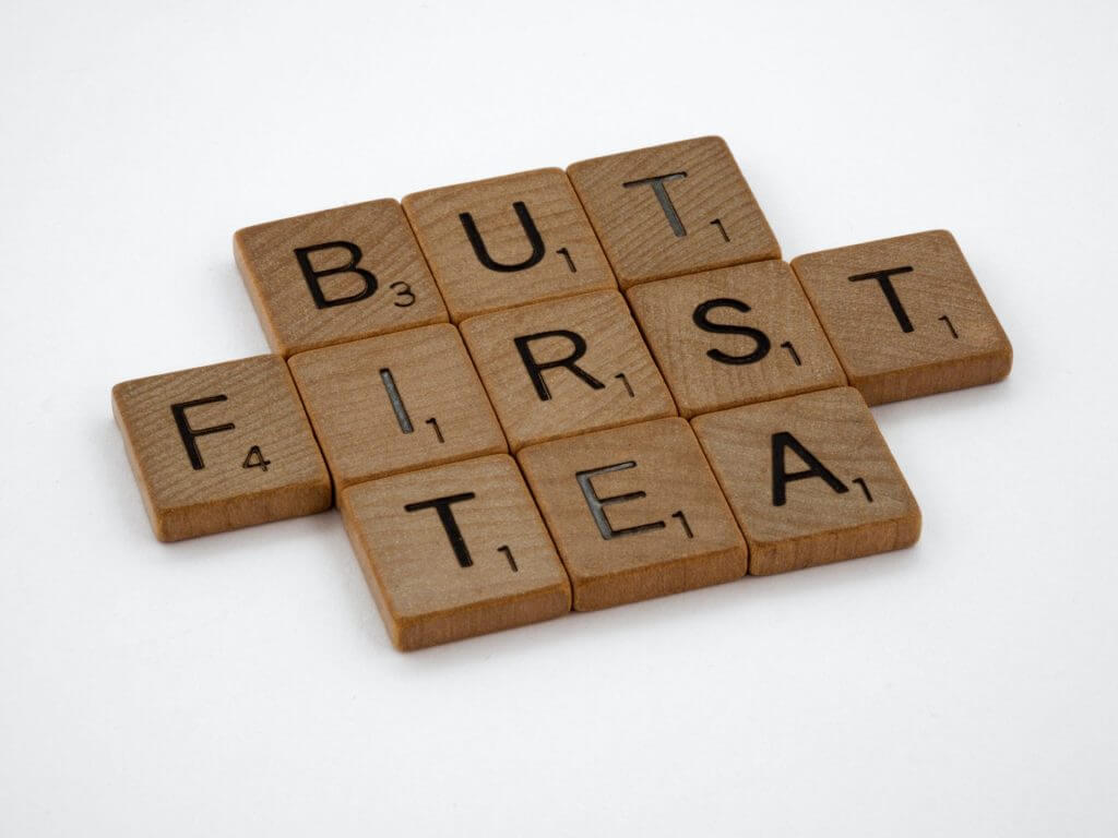 Ein Scrabble-Brett mit dem Wort „aber erster Tee“.