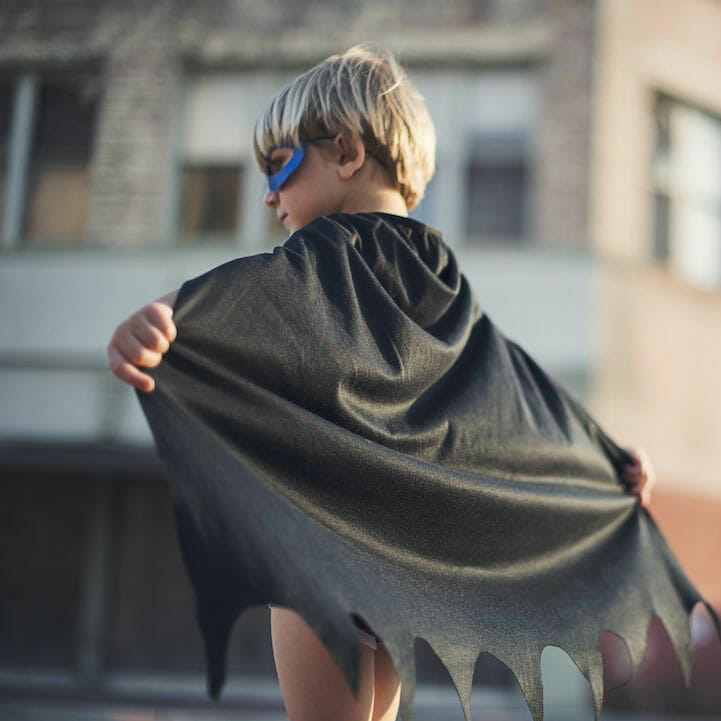 Ein kleiner Junge, der einen Batman-Umhang trägt.