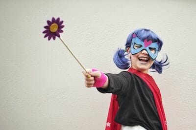 Ein als Superheldin verkleidetes Mädchen hält eine Blume in der Hand.