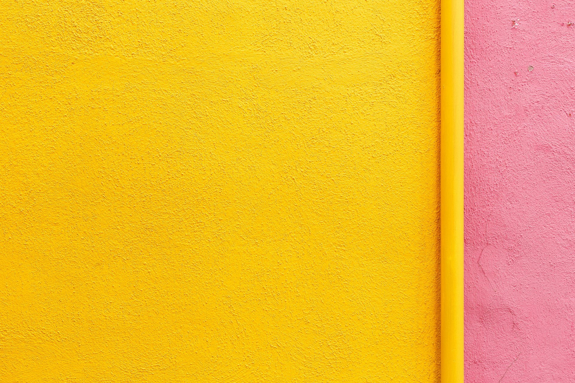 Gelbe und rosa strukturierte Wände treffen an einer Ecke mit einer dünnen gelben Trennlinie zusammen.